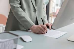 A man wearing a grey suit signing a contract