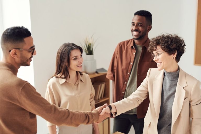 a group of young professionals smiling and shaking hands