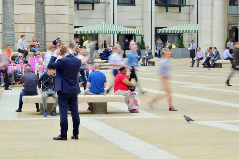 Man in a suit, talking on the phone, crowd of people, pigeon, umbrellas, London